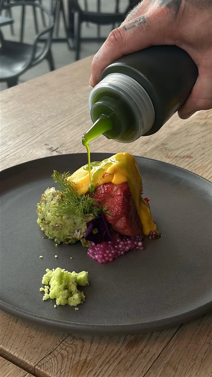 Finishing-Touch: Kräuteröl wird über ein Gericht mit Randen und Mango-Textur gegossen